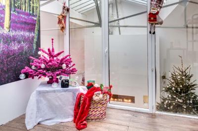 Table de fête décorée avec vaisselle élégante, sapin de Noël illuminé et cheminée allumée en arrière-plan.