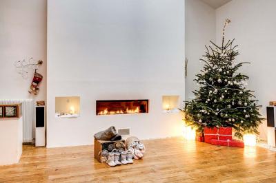 Table de fête décorée avec vaisselle élégante, sapin de Noël illuminé et cheminée allumée en arrière-plan.