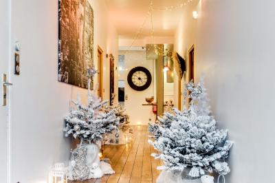 Table de fête décorée avec vaisselle élégante, sapin de Noël illuminé et cheminée allumée en arrière-plan.
