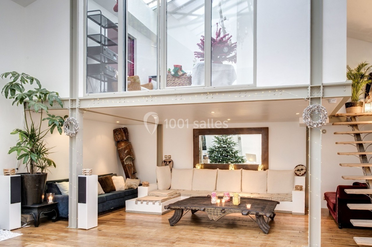 Salon lumineux avec mezzanine, canapé beige, table basse en bois, plantes et décoration chaleureuse dans un style moderne.