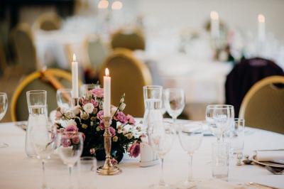 Table de fête décorée avec vaisselle élégante, sapin de Noël illuminé et cheminée allumée en arrière-plan.