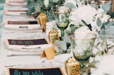 Table de fête décorée avec vaisselle élégante, sapin de Noël illuminé et cheminée allumée en arrière-plan.