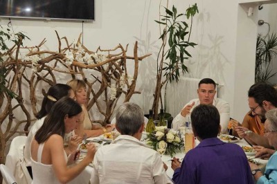 Table de fête décorée avec vaisselle élégante, sapin de Noël illuminé et cheminée allumée en arrière-plan.