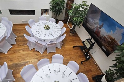 Table de fête décorée avec vaisselle élégante, sapin de Noël illuminé et cheminée allumée en arrière-plan.