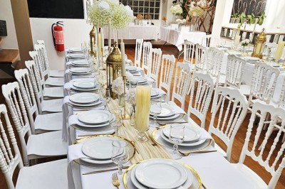 Table de fête décorée avec vaisselle élégante, sapin de Noël illuminé et cheminée allumée en arrière-plan.