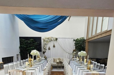 Table de fête décorée avec vaisselle élégante, sapin de Noël illuminé et cheminée allumée en arrière-plan.