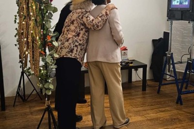 Table de fête décorée avec vaisselle élégante, sapin de Noël illuminé et cheminée allumée en arrière-plan.