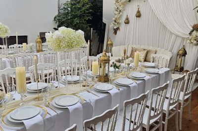 Table de fête décorée avec vaisselle élégante, sapin de Noël illuminé et cheminée allumée en arrière-plan.