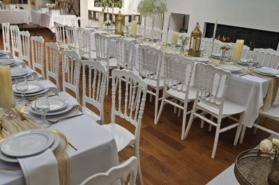 Table de fête décorée avec vaisselle élégante, sapin de Noël illuminé et cheminée allumée en arrière-plan.