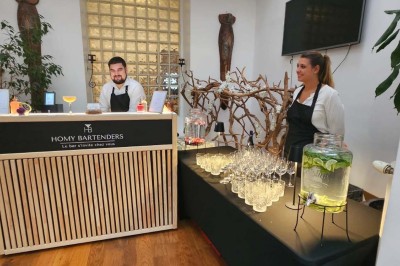 Table de fête décorée avec vaisselle élégante, sapin de Noël illuminé et cheminée allumée en arrière-plan.