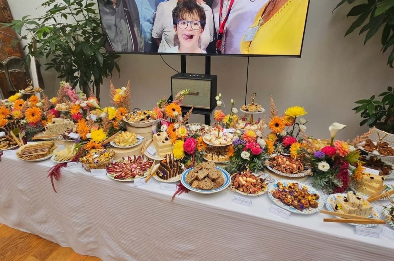 Buffet décoré de fleurs colorées, proposant divers plats et amuse-bouches sur une table blanche dans une salle.