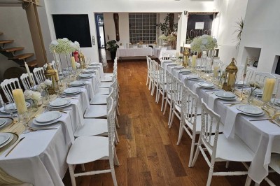 Table de fête décorée avec vaisselle élégante, sapin de Noël illuminé et cheminée allumée en arrière-plan.