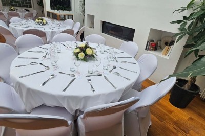 Table de fête décorée avec vaisselle élégante, sapin de Noël illuminé et cheminée allumée en arrière-plan.