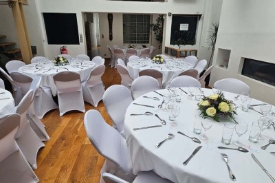 Table de fête décorée avec vaisselle élégante, sapin de Noël illuminé et cheminée allumée en arrière-plan.