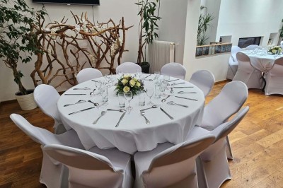 Table de fête décorée avec vaisselle élégante, sapin de Noël illuminé et cheminée allumée en arrière-plan.