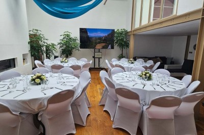 Table de fête décorée avec vaisselle élégante, sapin de Noël illuminé et cheminée allumée en arrière-plan.