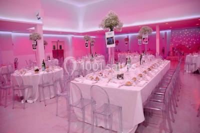 Mains d'un couple portant des alliances, posées sur un bouquet de fleurs blanches et violettes.