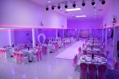 Mains d'un couple portant des alliances, posées sur un bouquet de fleurs blanches et violettes.