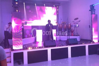 Mains d'un couple portant des alliances, posées sur un bouquet de fleurs blanches et violettes.