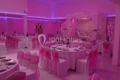 Mains d'un couple portant des alliances, posées sur un bouquet de fleurs blanches et violettes.