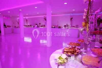 Mains d'un couple portant des alliances, posées sur un bouquet de fleurs blanches et violettes.