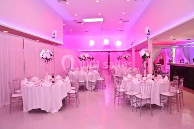 Mains d'un couple portant des alliances, posées sur un bouquet de fleurs blanches et violettes.