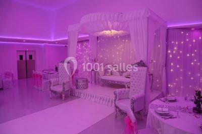 Mains d'un couple portant des alliances, posées sur un bouquet de fleurs blanches et violettes.