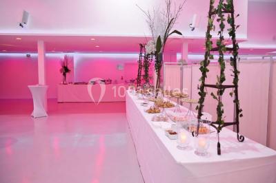 Mains d'un couple portant des alliances, posées sur un bouquet de fleurs blanches et violettes.