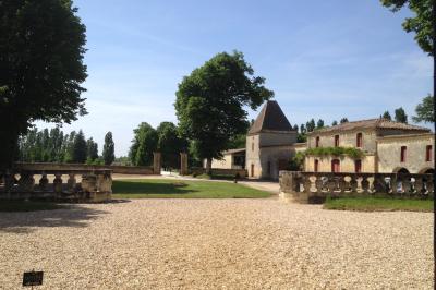 Château en pierre éclairé à la tombée de la nuit, entouré d'arbres et surmonté d'un ciel nuageux.