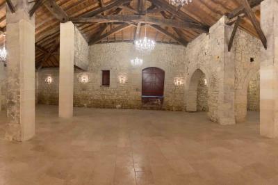 Château en pierre éclairé à la tombée de la nuit, entouré d'arbres et surmonté d'un ciel nuageux.