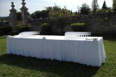 Château en pierre éclairé à la tombée de la nuit, entouré d'arbres et surmonté d'un ciel nuageux.