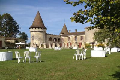 Château en pierre éclairé à la tombée de la nuit, entouré d'arbres et surmonté d'un ciel nuageux.