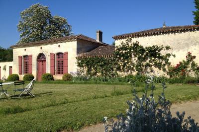 Château en pierre éclairé à la tombée de la nuit, entouré d'arbres et surmonté d'un ciel nuageux.