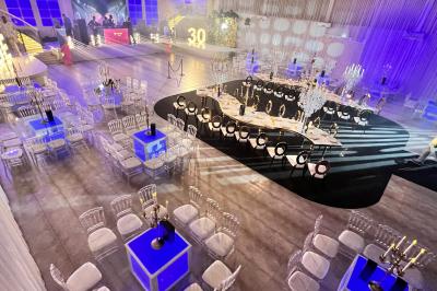 Voiture de sport verte aux portes papillon ouvertes, entourée de fumée et d'une foule dans un lieu éclairé.