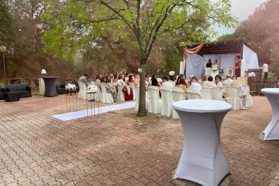 Mobilier de jardin en résine tressée disposé sur une terrasse en béton, entouré d'arbres et de verdure.