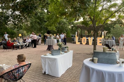 Mobilier de jardin en résine tressée disposé sur une terrasse en béton, entouré d'arbres et de verdure.
