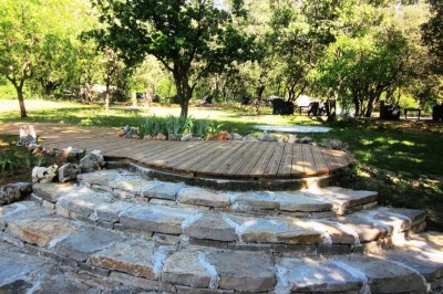 Mobilier de jardin en résine tressée disposé sur une terrasse en béton, entouré d'arbres et de verdure.