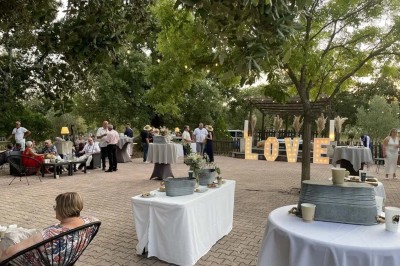 Mobilier de jardin en résine tressée disposé sur une terrasse en béton, entouré d'arbres et de verdure.