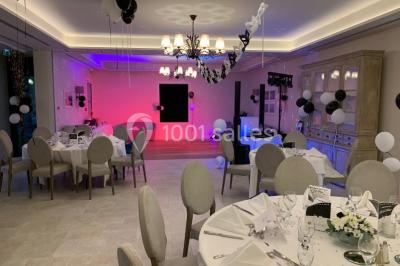 Salle de bain avec baignoire, lavabo moderne sur meuble noir, miroir mural et lumière naturelle par une fenêtre.
