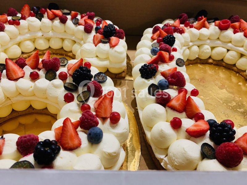 Gâteau en forme de chiffres décoré de crème, fraises, framboises, myrtilles, groseilles et mûres sur un plateau doré.