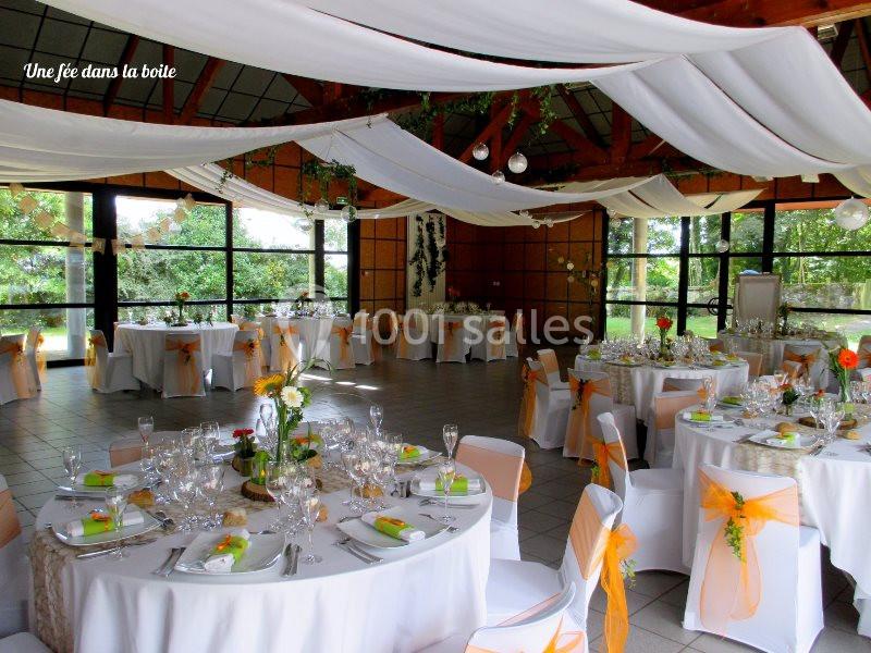 Location salle Plouay (Morbihan) - Domaine de Manehouarn #6 Salle de réception décorée avec des tables rondes, nappes blanches, chaises ornées de rubans orange et plafonds drapés.