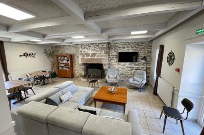 Miniature Location salle Plouay (Morbihan) - Domaine de Manehouarn #7 Cuisine ouverte avec table ronde, chaises, fauteuils, téléviseur, et grande fenêtre laissant entrer la lumière naturelle.