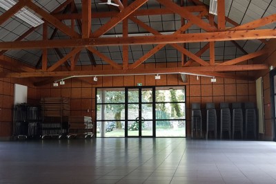 Cuisine ouverte avec table ronde, chaises, fauteuils, téléviseur, et grande fenêtre laissant entrer la lumière naturelle.