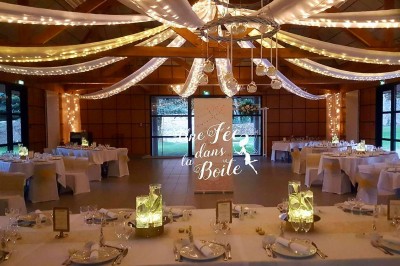 Cuisine ouverte avec table ronde, chaises, fauteuils, téléviseur, et grande fenêtre laissant entrer la lumière naturelle.