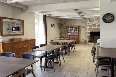 Cuisine professionnelle équipée avec réfrigérateur, plan de travail en inox, évier, plaques de cuisson et carrelage mural.