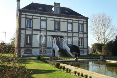 Paysage automnal avec un lac reflétant des arbres aux feuilles rouges et orangées sous un ciel nuageux.