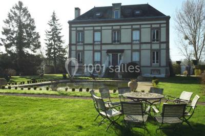 Paysage automnal avec un lac reflétant des arbres aux feuilles rouges et orangées sous un ciel nuageux.