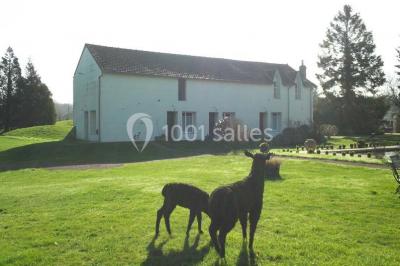 Paysage automnal avec un lac reflétant des arbres aux feuilles rouges et orangées sous un ciel nuageux.