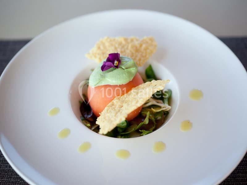 Assiette gastronomique avec un dôme de tomate, mousse verte, chips croustillantes et garniture de salade.
