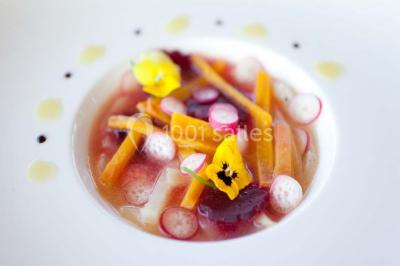 Paysage automnal avec un lac reflétant des arbres aux feuilles rouges et orangées sous un ciel nuageux.